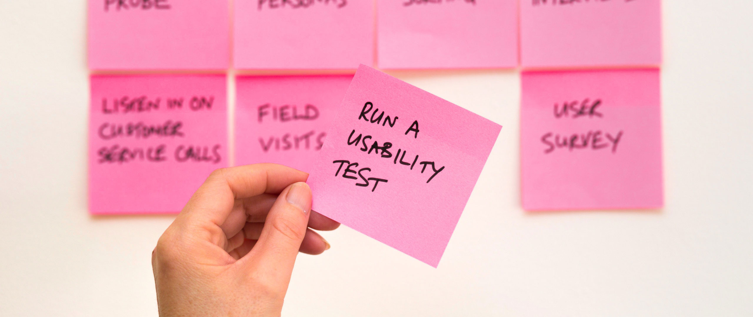 Een bord met Post-its waarbij één wordt vast gehouden met de tekst 'Run a usability test'